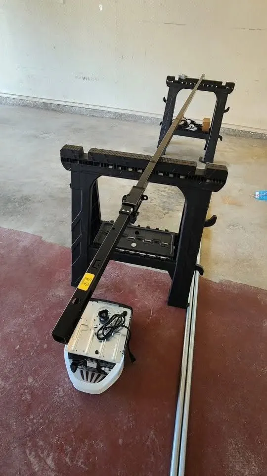 New garage door opener with its rail fully assembled, resting on sawhorses on a garage floor